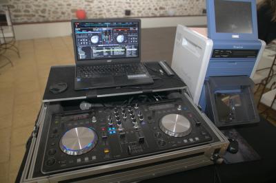 Table de mixage DJ professionnelle avec plusieurs platines, écrans et un QR code visible en arrière-plan.