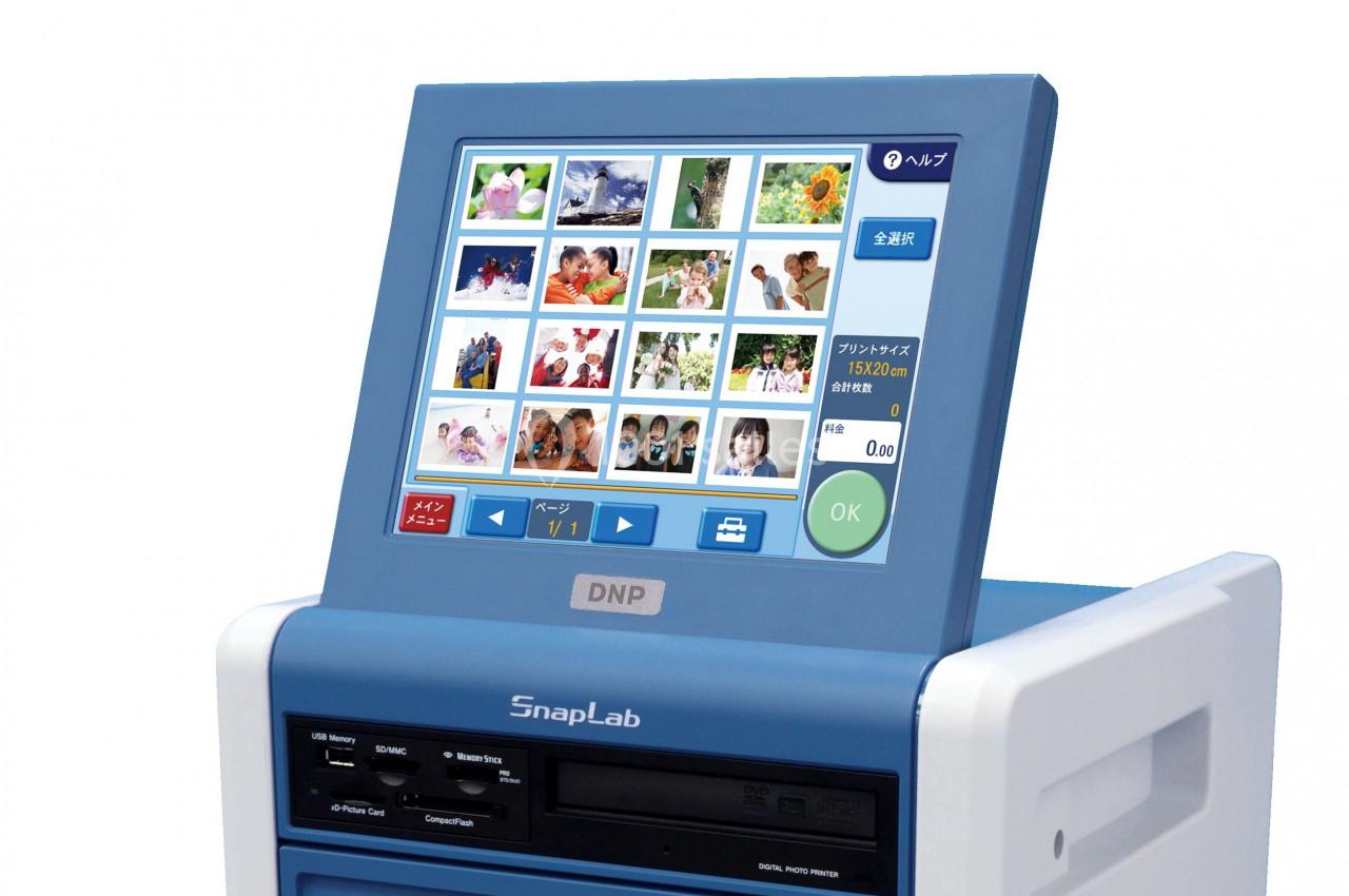 Écran tactile d'une borne photo affichant des vignettes d'images pour la sélection et l'impression.