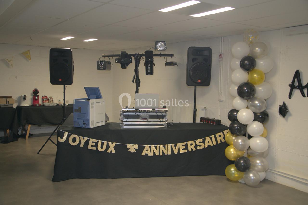 Table de DJ décorée pour un anniversaire, avec des ballons noirs, blancs et dorés, et une bannière ’Joyeux Anniversaire’.