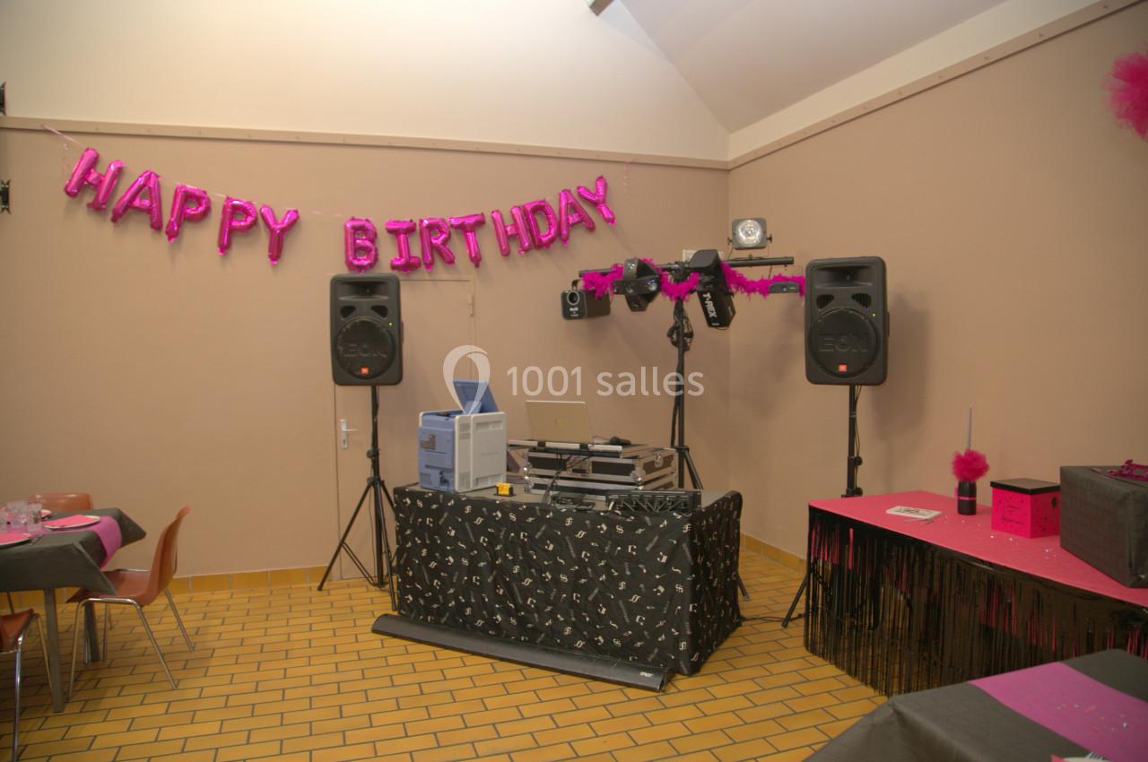 Salle décorée pour un anniversaire avec une table de mixage, des enceintes et une bannière ’Happy Birthday’.