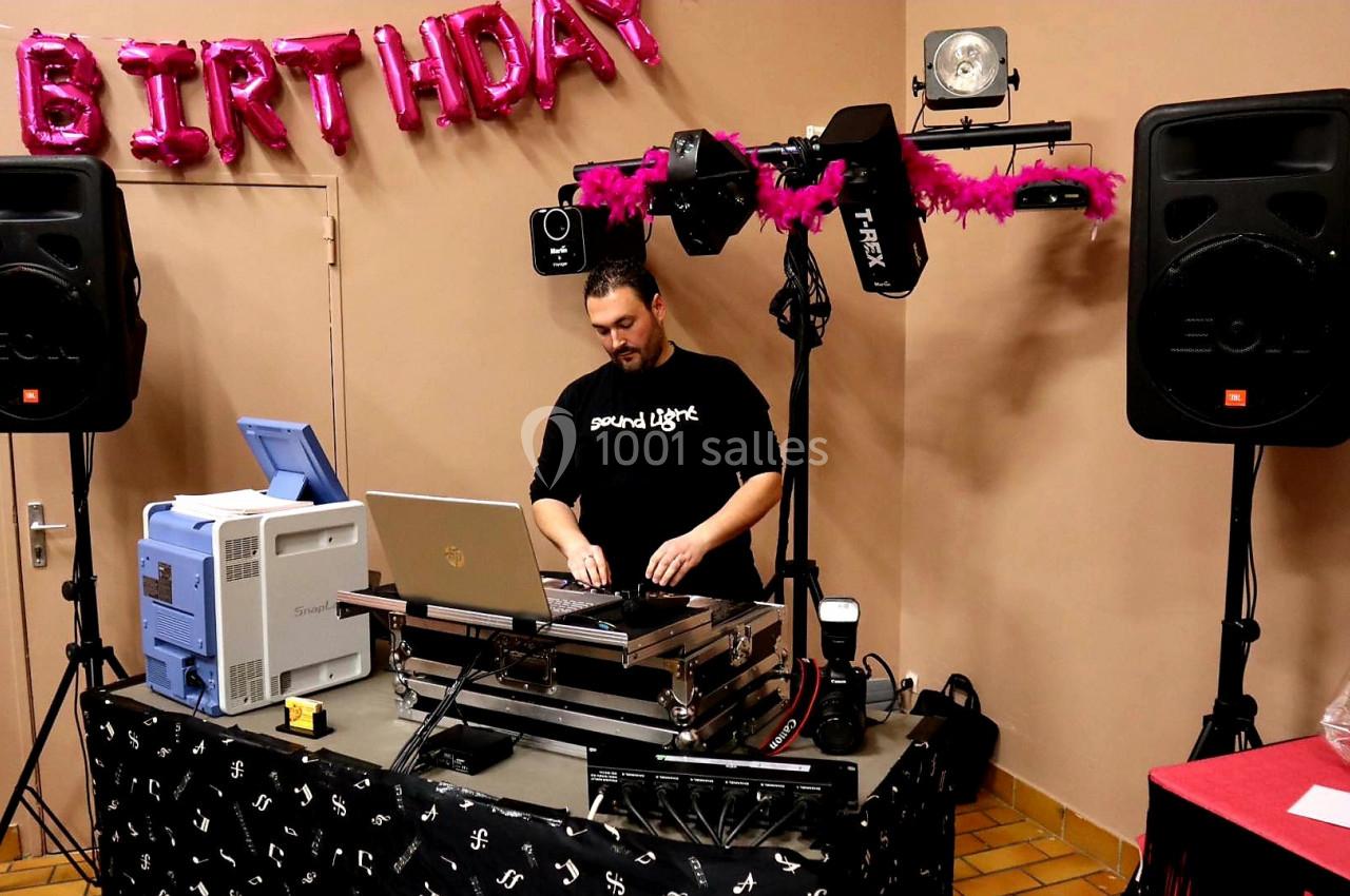 Un DJ mixant de la musique sur une table équipée d'un ordinateur et de matériel audio lors d'une fête d'anniversaire.