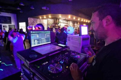 Table de mixage DJ professionnelle avec plusieurs platines, écrans et un QR code visible en arrière-plan.