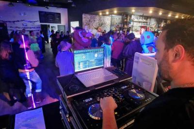 Table de mixage DJ professionnelle avec plusieurs platines, écrans et un QR code visible en arrière-plan.