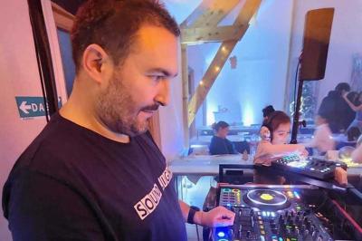 Table de mixage DJ professionnelle avec plusieurs platines, écrans et un QR code visible en arrière-plan.