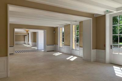 Vue d'un arbre à travers une fenêtre cintrée, encadrée par un intérieur lumineux avec un luminaire suspendu.