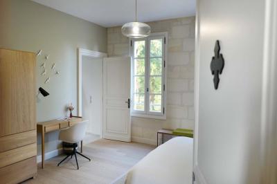 Vue d'un arbre à travers une fenêtre cintrée, encadrée par un intérieur lumineux avec un luminaire suspendu.