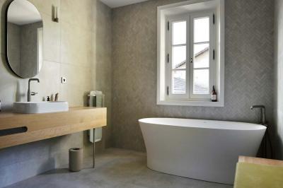 Vue d'un arbre à travers une porte vitrée, encadrée par un intérieur lumineux avec un luminaire suspendu.