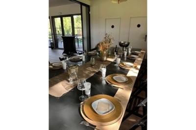 Chambre lumineuse avec lit double, bureau, coin salon, kitchenette et vue sur un jardin à travers une baie vitrée.