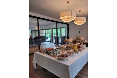 Chambre lumineuse avec lit double, bureau, coin salon, kitchenette et vue sur un jardin à travers une baie vitrée.