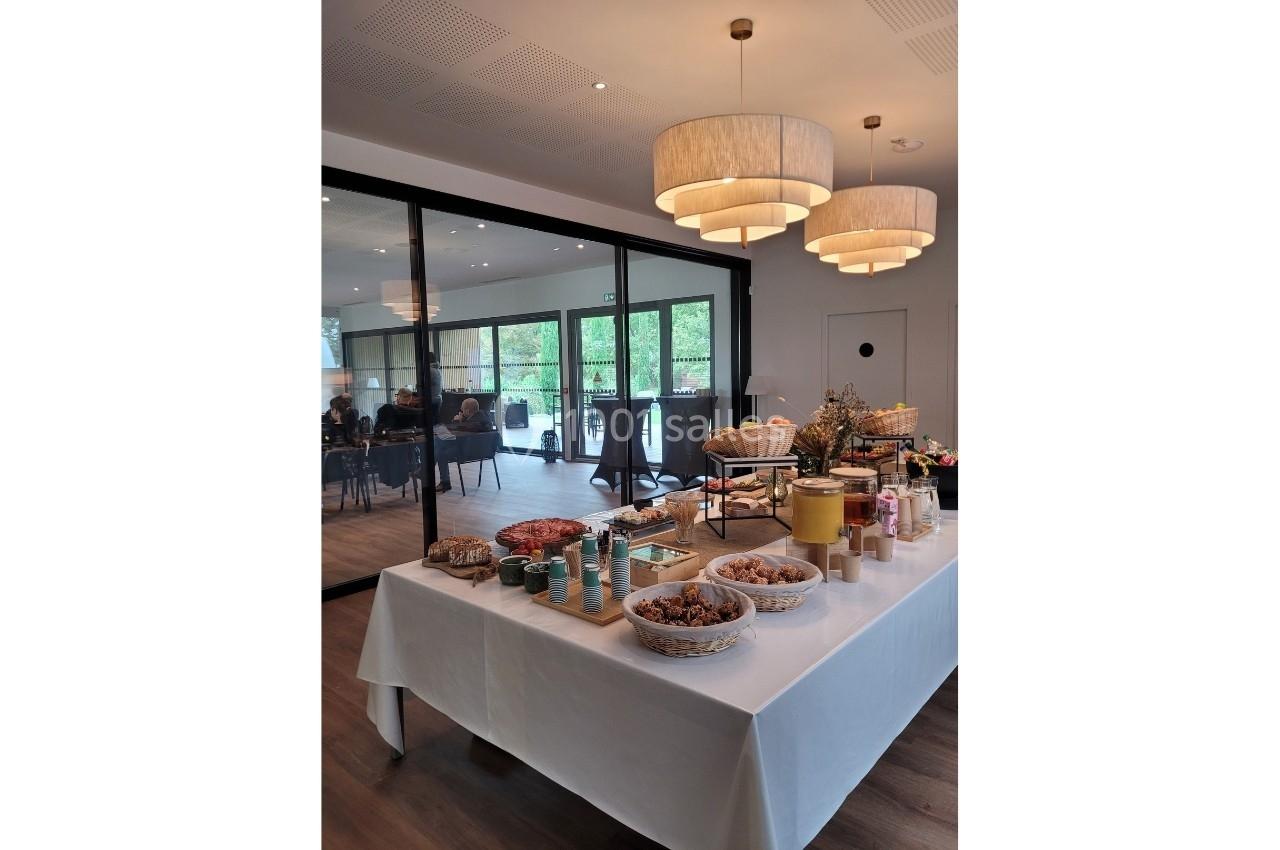 Table dressée avec des produits alimentaires variés, dans une salle lumineuse avec des personnes en arrière-plan.