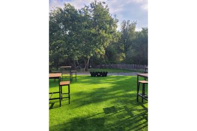 Chambre lumineuse avec lit double, bureau, coin salon, kitchenette et vue sur un jardin à travers une baie vitrée.