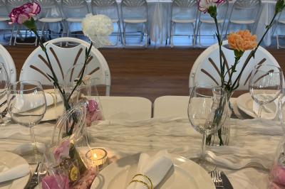 Terrasse moderne avec mobilier en plastique et bois, entourée de verdure et partiellement ombragée par un arbre.
