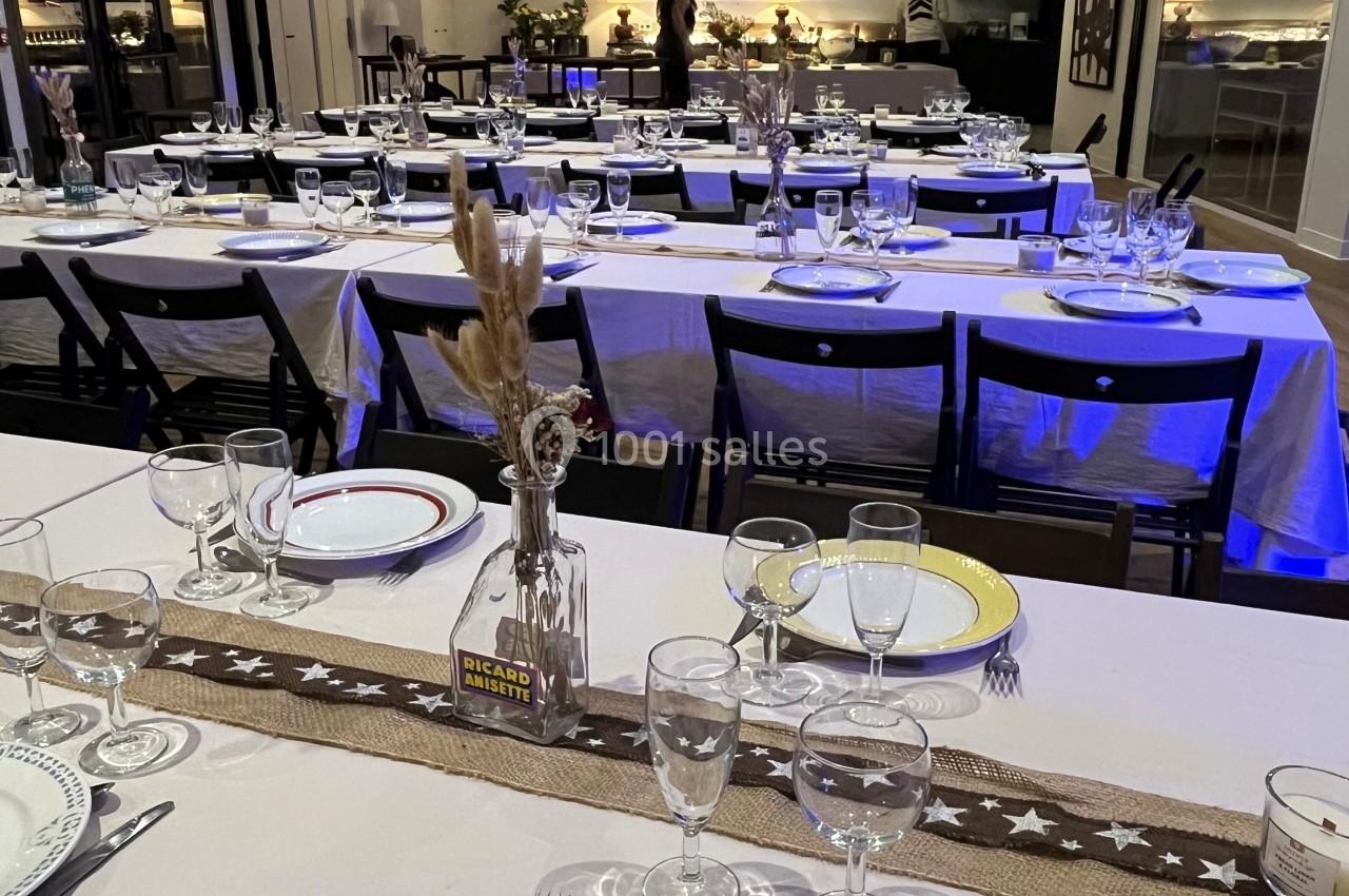 Salle de réception décorée avec des tables dressées, assiettes colorées et ambiance lumineuse chaleureuse.