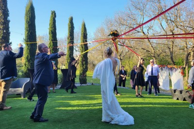 Terrasse moderne avec mobilier en plastique et bois, entourée de verdure et partiellement ombragée par un arbre.