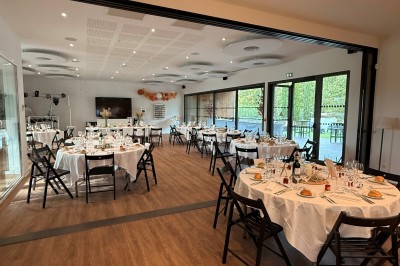 Chambre lumineuse avec lit double, bureau, coin salon, kitchenette et vue sur un jardin à travers une baie vitrée.