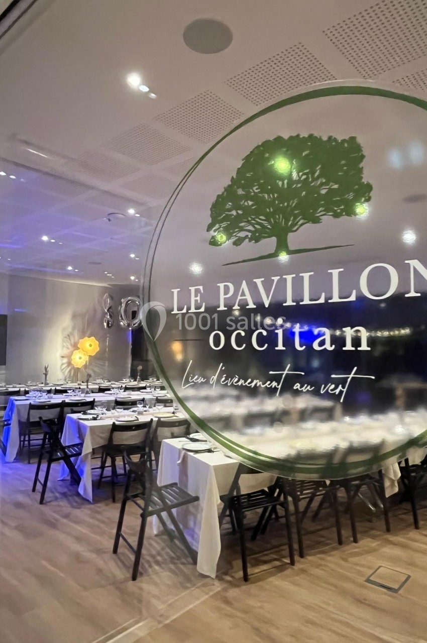 Salle de réception élégamment décorée, vue à travers une vitre avec le logo ’Le Pavillon Occitan’.