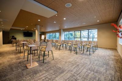 Salle de restaurant lumineuse avec tables en bois, banquettes rembourrées et décor mural en bois.
