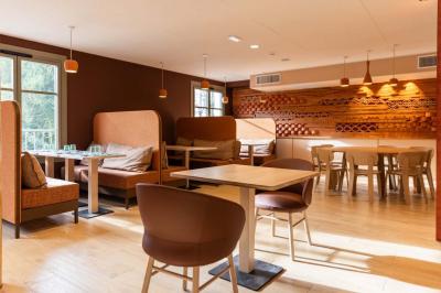 Salle de restaurant lumineuse avec tables en bois, banquettes rembourrées et décor mural en bois.