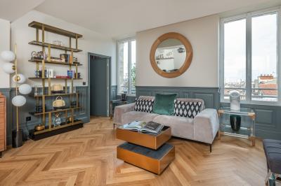 Salle à manger moderne avec table ronde, chaises violettes, parquet en chevrons, étagères et coin café.