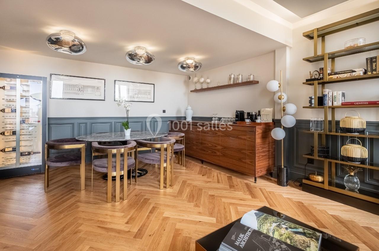 Salle à manger moderne avec table ronde, chaises violettes, parquet en chevrons, étagères et coin café.
