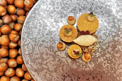 Assiette gastronomique composée de desserts aux noisettes, présentée sur un fond texturé et entourée de noisettes entières.