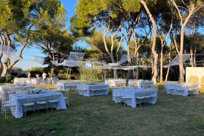 Grand chapiteau beige éclairé par des guirlandes lumineuses, abritant des tables rondes dressées pour un événement en plein…