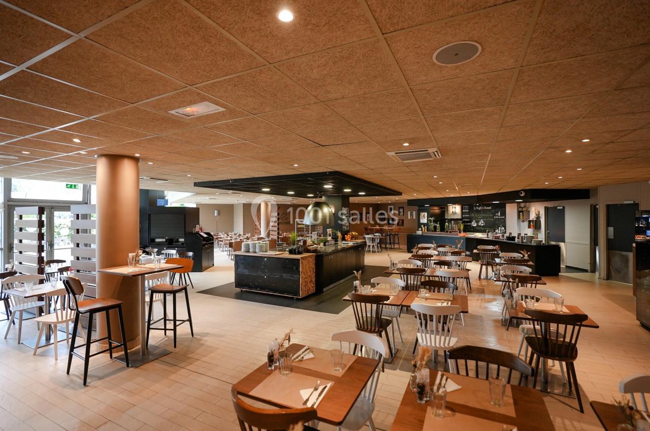 Salle de restaurant lumineuse avec tables en bois, chaises assorties et buffet central moderne.