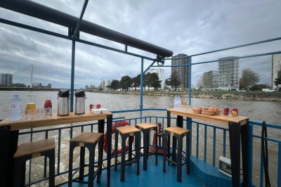 Fontaine à bière avec gobelets réutilisables empilés, posée sur un comptoir en bois près d'un tableau de menu.