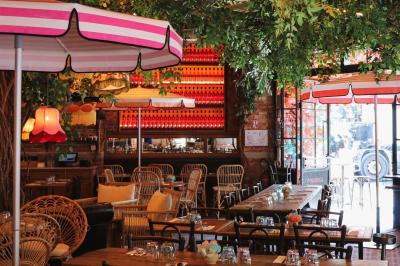 Plateau avec un café, un cannelé, une tartelette, une brioche, de la crème et des verres sur une table rouge.