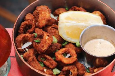 Plateau avec un café, un cannelé, une tartelette, une brioche, de la crème et des verres sur une table rouge.
