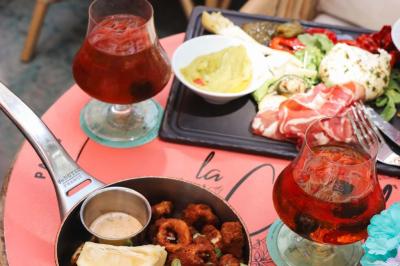 Plateau avec un café, un cannelé, une tartelette, une brioche, de la crème et des verres sur une table rouge.