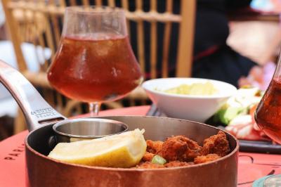 Plateau avec un café, un cannelé, une tartelette, une brioche, de la crème et des verres sur une table rouge.