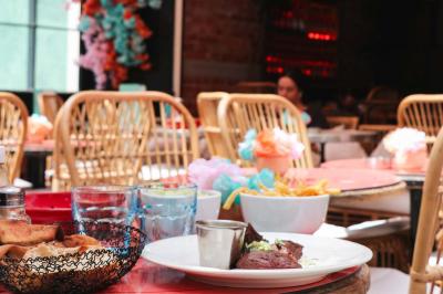 Plateau avec un café, un cannelé, une tartelette, une brioche, de la crème et des verres sur une table rouge.