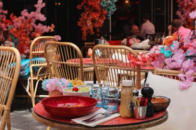 Plateau avec un café, un cannelé, une tartelette, une brioche, de la crème et des verres sur une table rouge.