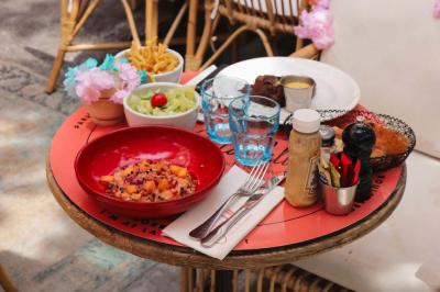 Plateau avec un café, un cannelé, une tartelette, une brioche, de la crème et des verres sur une table rouge.