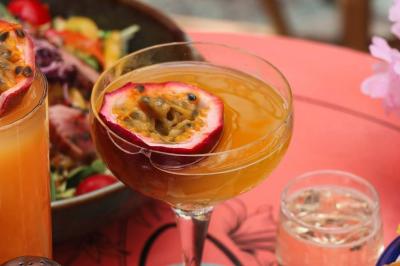 Plateau avec un café, un cannelé, une tartelette, une brioche, de la crème et des verres sur une table rouge.