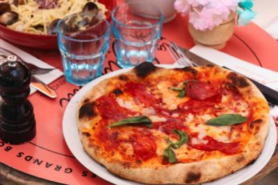 Plateau avec un café, un cannelé, une tartelette, une brioche, de la crème et des verres sur une table rouge.