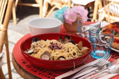 Plateau avec un café, un cannelé, une tartelette, une brioche, de la crème et des verres sur une table rouge.
