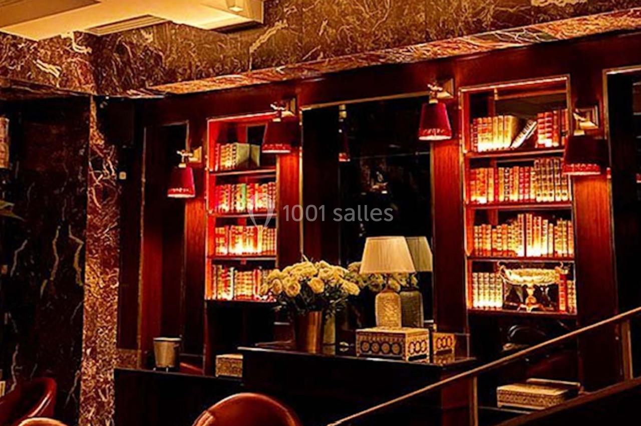 Bibliothèque éclairée par des lumières chaudes dans un intérieur élégant avec fauteuils en cuir et décorations raffinées.