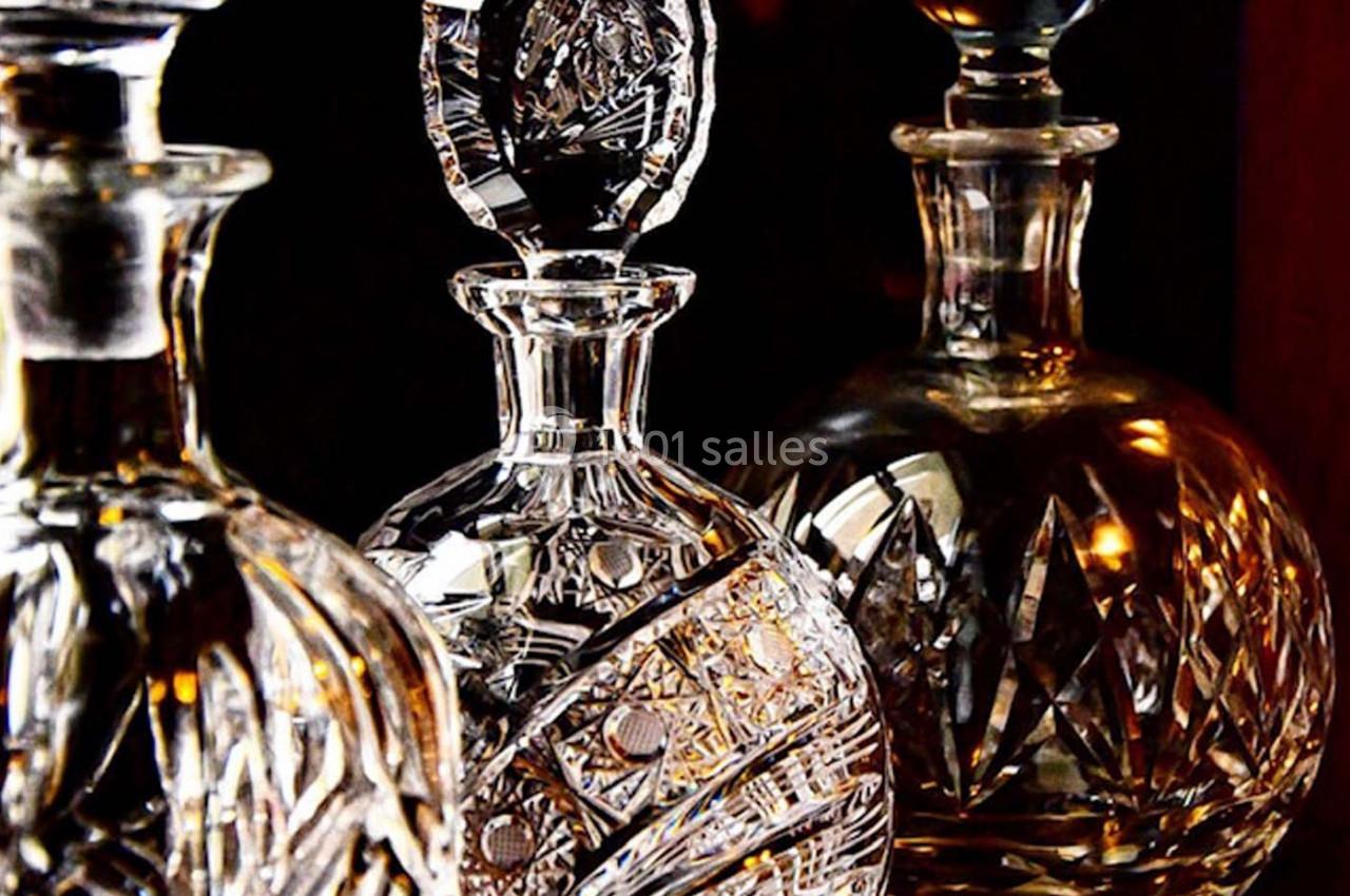 Trois carafes en cristal finement gravées, éclairées par une lumière chaude mettant en valeur leurs motifs détaillés.