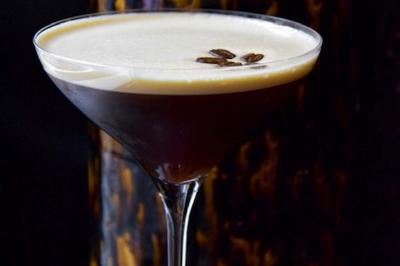 Verre à cocktail rempli d'un espresso martini, surmonté d'une mousse crémeuse et décoré de grains de café.