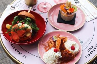 Assiette de sandwichs triangulaires et planche de pizza garnie de mozzarella et tomates, avec verres de vin rouge.