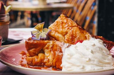 Assiette de sandwichs triangulaires et planche de pizza garnie de mozzarella et tomates, avec verres de vin rouge.