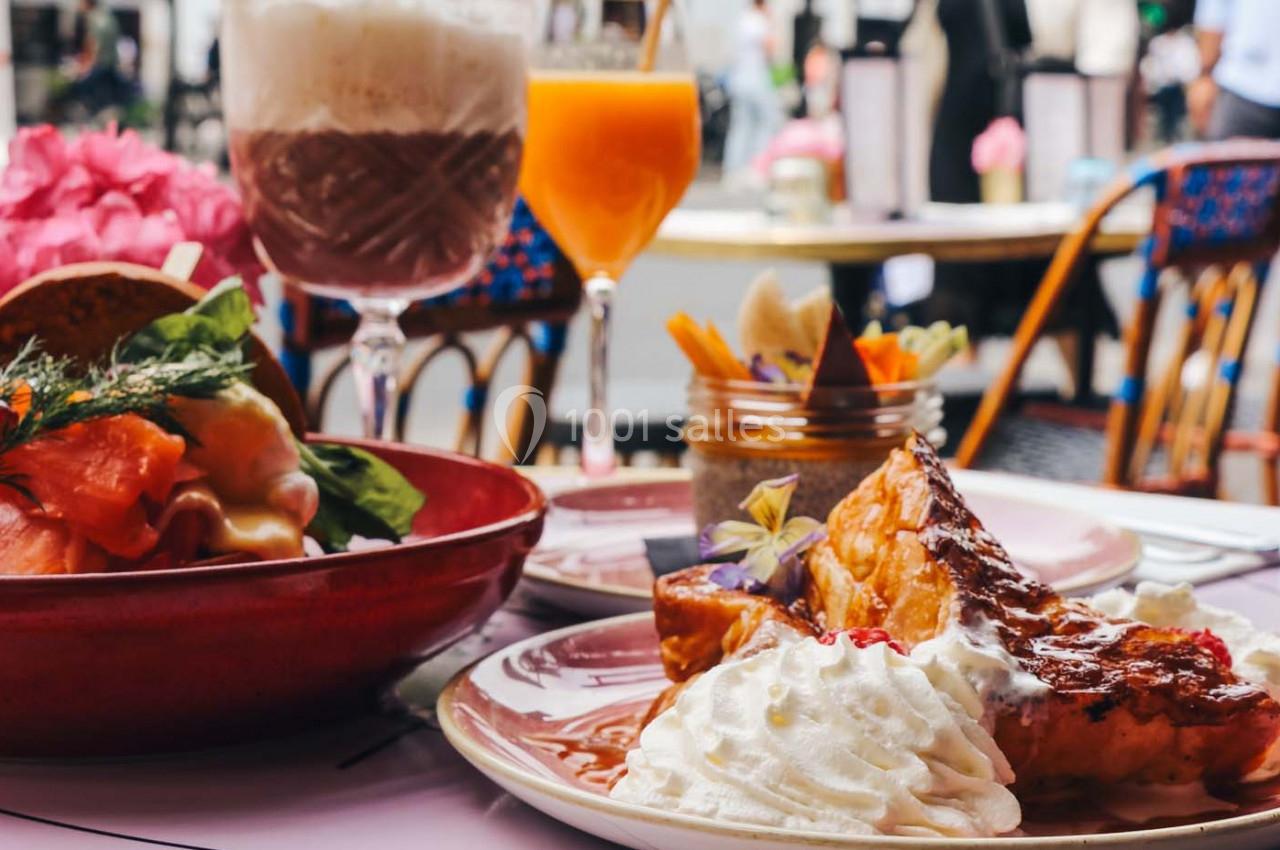 Assiette de pain perdu avec chantilly, saumon fumé et boissons sur une table en terrasse.