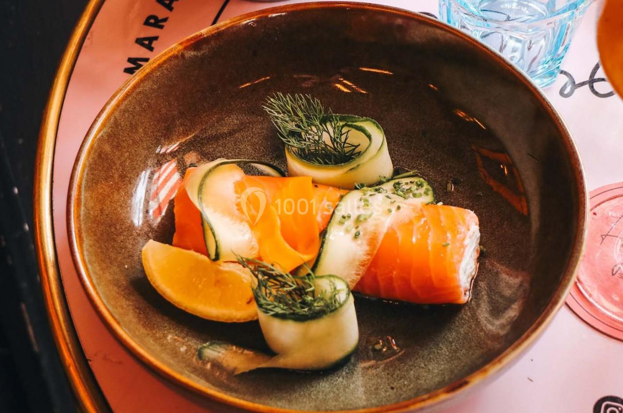 Assiette contenant des roulés de saumon et de concombre garnis d'aneth, accompagnés d'un quartier de citron.