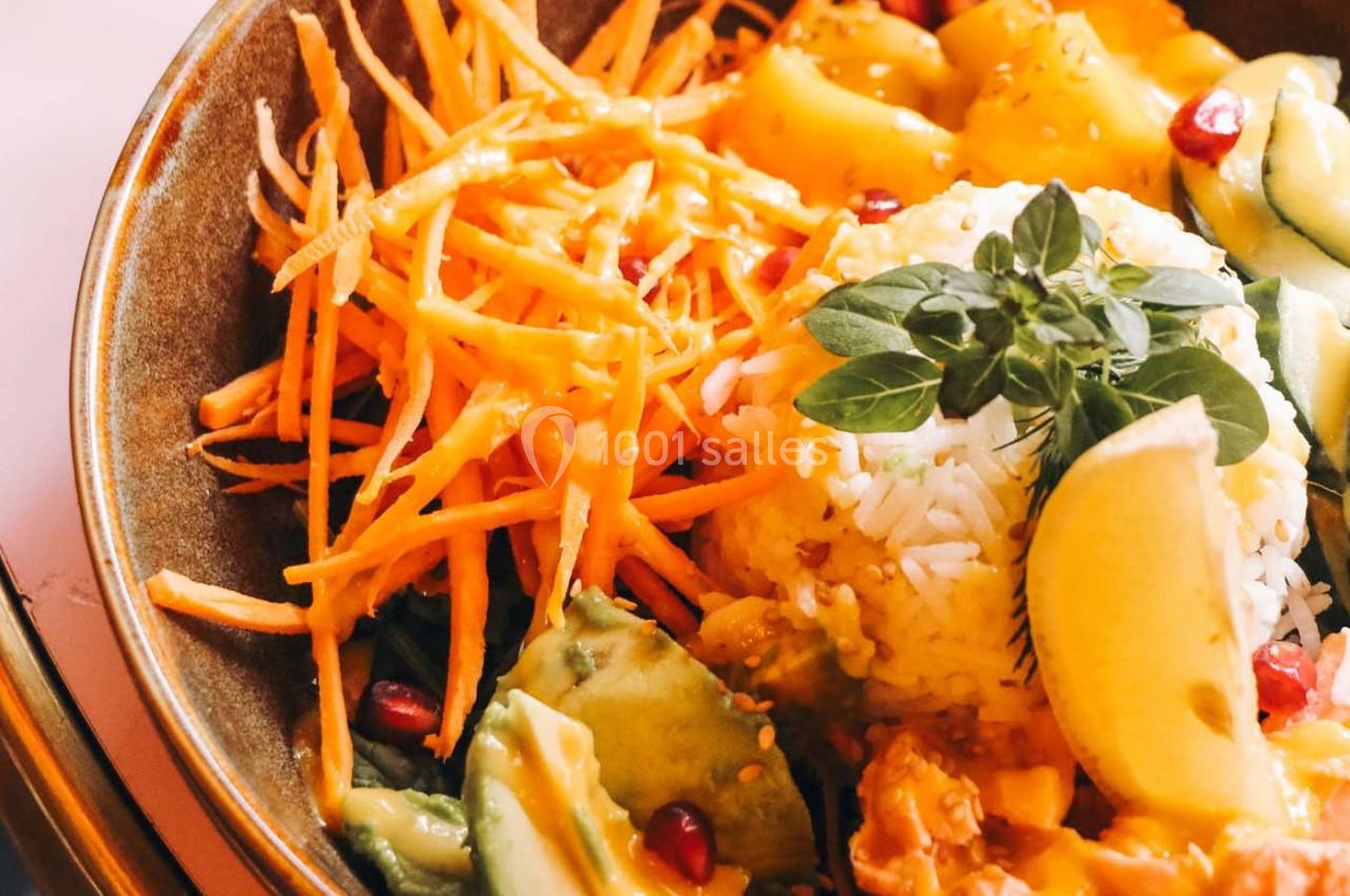 Bol coloré avec riz, carottes râpées, avocat, grenade, citron et herbes fraîches.