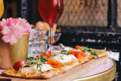 Assiette de sandwichs triangulaires et planche de pizza garnie de mozzarella et tomates, avec verres de vin rouge.