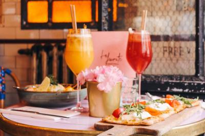 Assiette de sandwichs triangulaires et planche de pizza garnie de mozzarella et tomates, avec verres de vin rouge.