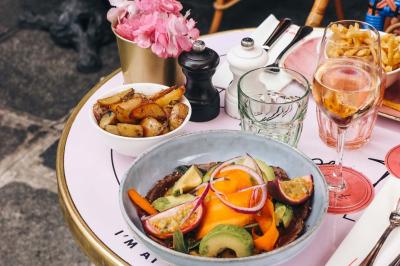 Assiette de sandwichs triangulaires et planche de pizza garnie de mozzarella et tomates, avec verres de vin rouge.