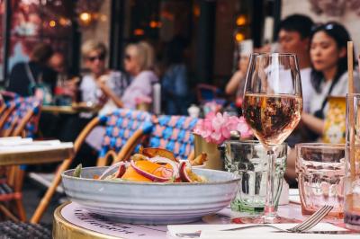 Assiette de sandwichs triangulaires et planche de pizza garnie de mozzarella et tomates, avec verres de vin rouge.